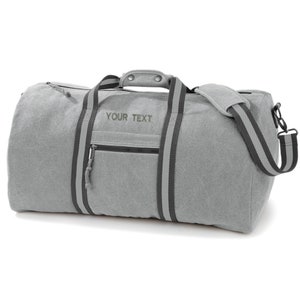 May include: Gray canvas duffel bag with black straps and a zippered pocket. The bag has a shoulder strap and the text "YOUR TEXT" is embroidered on the front.