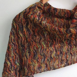 May include: A brown, orange, and green knitted shawl with a lacy pattern.