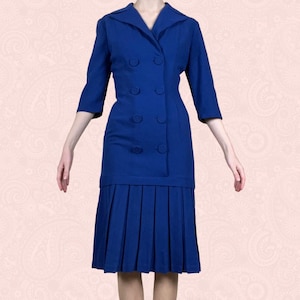 May include: A vintage cobalt blue dress with a double-breasted jacket-style top and a pleated skirt. The dress features a collared neckline and three-quarter sleeves. The buttons are the same color as the dress.