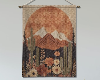 May include: A tapestry wall hanging featuring a desert landscape with a large orange sun, mountains, cacti, and flowers. The tapestry is rectangular and hangs from a wooden rod with a beige cord.