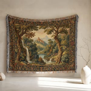 Può includere: Arazzo tessuto raffigurante un paesaggio con cascate, alberi e un castello. L'arazzo ha un bordo dettagliato e bordi con frange, con uno stile classico e vintage. La tavolozza dei colori comprende verdi, marroni e blu.