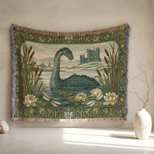 May include: Woven tapestry featuring a teal Loch Ness Monster in a lake with water lilies, cattails, and a castle in the background. The tapestry has a decorative border with fringe edges, in shades of green, beige, and brown.