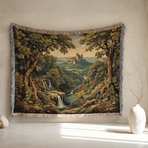Könnte beinhalten: Gewebte Tapisserie mit einer malerischen Landschaft mit einer Burg, Wasserfällen und üppigem Grün. Das Kunstwerk wird von großen Bäumen umrahmt, die einen natürlichen Rahmen bilden. Die Tapisserie hat einen Fransenrand und wird an einer Wand präsentiert.