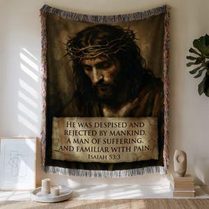 Puede incluir: Tapiz tejido con un retrato de Jesús con una corona de espinas. La imagen incluye el texto "HE WAS DESPISED AND REJECTED BY MANKIND, A MAN OF SUFFERING, AND FAMILIAR WITH PAIN. ISAIAH 53:3". El tapiz tiene un borde con flecos.