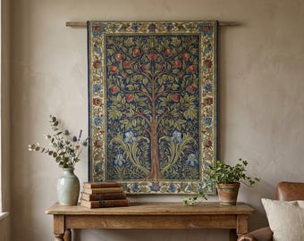 May include: A rectangular wall tapestry featuring a central tree with red fruit, green leaves, and blue iris flowers against a dark blue background, framed by a decorative border with floral motifs, hanging from a wooden rod on a beige wall.