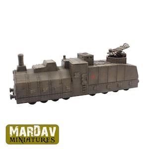 Puede incluir: Un modelo en miniatura de tren blindado con un acabado en verde oliva oscuro y detalles de remaches visibles a lo largo del casco. La locomotora presenta un pequeño emblema de estrella roja en el lateral y una torreta de armas en la parte trasera.