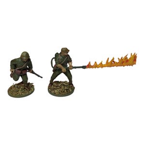 Puede incluir: Dos figuras en miniatura pintadas de soldados, uno sosteniendo un rifle y el otro un lanzallamas con un chorro de llamas naranjas.