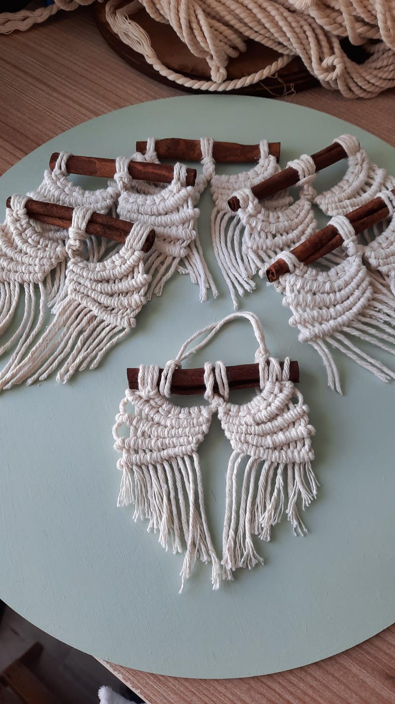 Pu&ograve; includere: Un set di sei arazzi da parete in macram&eacute; con accenti di bastoncino di cannella. Ogni arazzo presenta un motivo geometrico con dettagli a frangia.