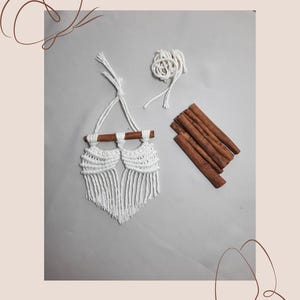 Pu&ograve; includere: Appeso a parete in macram&egrave; bianco con due bastoncini di cannella, un gomitolo di filo bianco e estremit&agrave; sciolte di filo bianco.