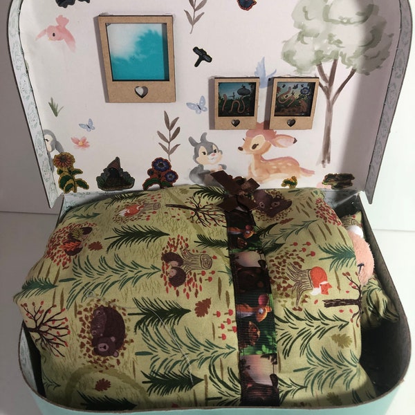 Une valise à jouets conçue pour faire une chambre confortable pour Superworm, avec parure de lit et oreiller faits main et son livre spécial !