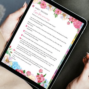 May include: A digital habit tracker displayed on a tablet, featuring floral watercolor accents. The screen shows text titled "Habit Tracker" with tips for success. The tablet is held by a person, with a stylus visible.