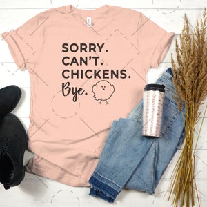 May include: A peach-coloured t-shirt with the text "SORRY. CAN'T. CHICKENS. Bye." and a small black and white cartoon chicken illustration.