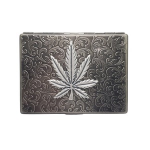 May include: A silver metal cigarette case with an embossed marijuana leaf design.