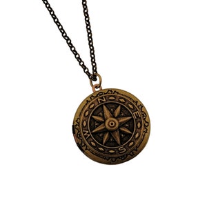 May include: A gold-toned compass pendant necklace with a detailed compass design and a black chain.
