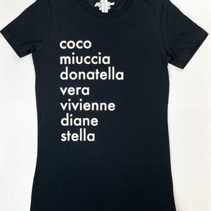 May include: Black t-shirt with white text that reads "coco miuccia donatella vera vivienne diane stella"