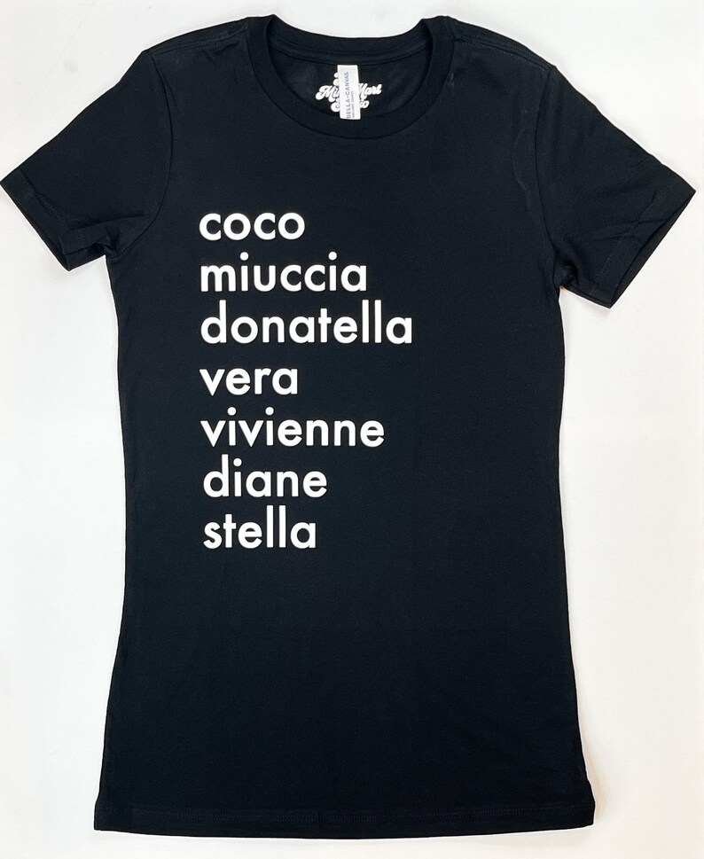 May include: Black t-shirt with white text that reads "coco miuccia donatella vera vivienne diane stella"