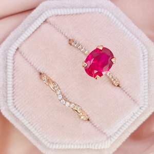 Peut inclure: Deux bagues en or avec une pierre ovale rose et de petites pierres claires. Les bagues sont dans un écrin à bagues en velours rose.