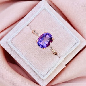 May include: A ring featuring a large oval amethyst gemstone set in a rose gold band with small diamonds on the band.