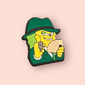 May include: A green and yellow cartoon character wearing a green fedora and a green suit. The character is holding a fan of cards in one hand and giving a thumbs up with the other hand.