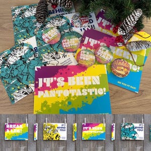 Può includere: Una collezione di biglietti di auguri, spille e elementi decorativi colorati con le scritte "IT'S BEEN PANTOTASTIC!" e "BREAK A LEG!". I biglietti presentano illustrazioni e sono decorati con pigne e verde.
