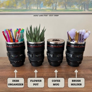 May include: Four black camera lens mugs with different items inside. The first mug has a variety of colorful pens, the second has a small green plant, the third has coffee beans, and the fourth has makeup brushes. The mugs are on a wooden surface with text below each mug: "Desk Organizer", "Flower Pot", "Coffee Mug", and "Brush Holder".