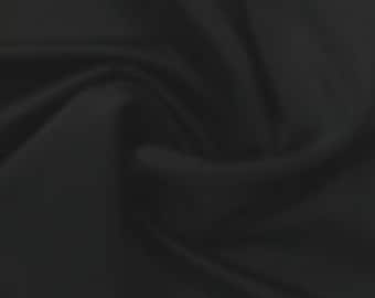 May include: A close-up of a black fabric with a smooth texture. The fabric is draped and folded, creating soft curves and folds.