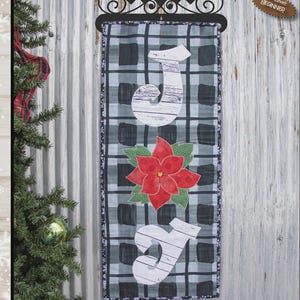 May include: A decorative wall hanging with the text "FULL OF JOY" and dimensions of 12" x 30". It features a plaid pattern, the letters "J" and a red poinsettia flower. The skill level is beginner.