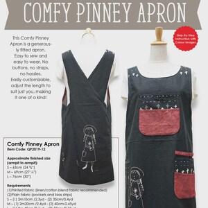 May include: A dark gray Comfy Pinney Apron pattern with a white t-shirt underneath. The apron features a cross-over design and pockets with red fabric. The text on the apron reads "COMFY PINNEY APRON". The apron sizes are S - 24 ¾", M - 27 ¼", and L - 30".