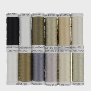 May include: A collection of Sulky 50 Wt. Cotton thread spools in various neutral colors, including black, white, and shades of beige and green. Each spool is labeled with the thread type and length.