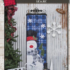 May include: A Jolly Snowman wall hanging, 12" x 33", with a beginner skill level. The design features a snowman with a black top hat, red hat, and plaid scarf. The words "Hello Winter" are embroidered on a blue plaid background.