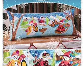 May include: A rectangular pillow with a winter village scene featuring snowmen, houses, and trees. The pillow has the text "Snowman Village Pillow" at the top. The bottom of the image shows three smaller images of snowmen. The brand name "Shabby Fabrics" is also visible.