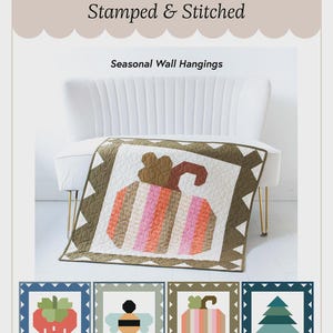 May include: A seasonal wall hanging quilt featuring a pumpkin design in shades of pink, orange, and brown. The quilt is displayed on a white couch. The image also includes smaller square designs of a strawberry, bee, pumpkin, and Christmas tree. Text reads "Stamped & Stitched".
