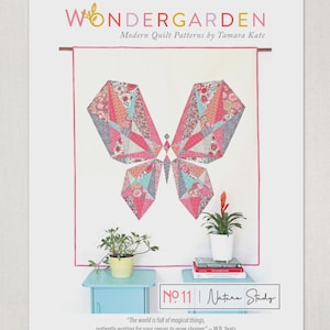 May include: A poster for "Wondergarden" modern quilt patterns by Tamara Kate. The design features a geometric butterfly quilt in pink, red, and blue. The poster includes the text "No. 11 | Nature Study" and a quote by W.B. Yeats.
