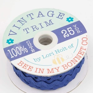 May include: A spool of blue vintage trim with a white label that reads "Vintage Trim 100% Cute by Lori Holt of Bee in My Bonnet Co. 25 yds."
