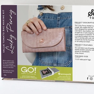 May include: A craft kit box for the "Lucky Penny" wallet by Sallie Tomato. The box features a pink wallet, and the text "Sallie Tomato Bag Making Kit". The finished size of the wallet is 7.5" wide and 4" high.