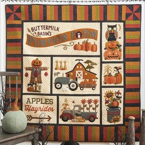 May include: A colorful quilt with a pumpkin farm theme, featuring a scarecrow, barn, tractor, and pumpkins. The quilt measures 63 x 63 inches. The design includes the text "BUTTERMILK BASIN'S PUMPKIN FARM".