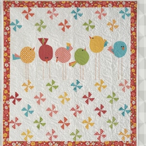 May include: A handmade quilt featuring six colorful bird appliqués on a white background. The birds are perched on thin stems, with pinwheel designs scattered around them. The quilt has a floral border and the word "Twitter" is displayed.