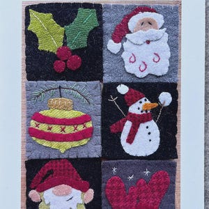 May include: A card featuring six felted Christmas-themed squares. Designs include holly, Santa, a Christmas ornament, a snowman, a gnome, and mittens. The text at the bottom reads "The Howell's Nest 2 1/2 x 2 1/2 Mini Woolie 6-pack (Winter Edition) Designed by: Emily Howell."