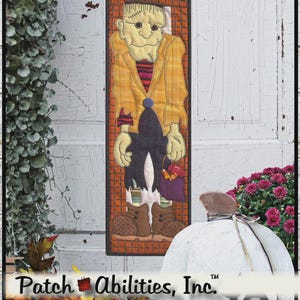 May include: A Halloween-themed fabric wall hanging featuring a Frankenstein's monster design. The artwork includes the word "FRANK" and "Boo!" in a decorative font. The dimensions are 6.5" x 21". The skill level is easy.