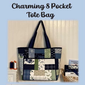 May include: A patchwork tote bag with navy blue handles and the text "Charming & Pocket Tote Bag". The bag features a variety of fabric patterns in shades of blue, green, and white. Finished size is 18 inches wide x 12 inches high x 6 inches.