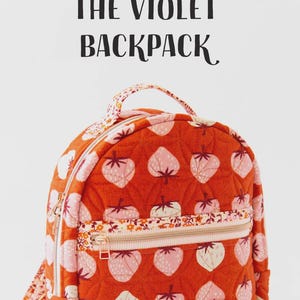 May include: A quilted backpack with a vibrant orange background and a pattern of pink and white strawberries. The backpack has a floral print zipper and strap, with the text "THE VIOLET BACKPACK" at the top.