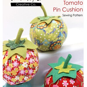 May include: Three handmade tomato pin cushions with green felt leaves and stems. The cushions are made from patterned fabric in red, yellow, and green. The text "Tomato Pin Cushion Sewing Pattern" is visible.