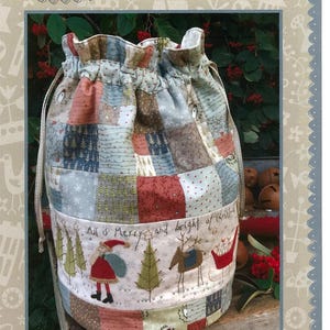 May include: A patchwork drawstring bag with a Christmas theme. The bag features a mix of fabrics in various colors and patterns. The bottom band has a festive design with Santa, reindeer, and trees. Text on the bag reads "All is Merry & Bright Bag".