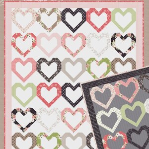May include: A quilt with a repeating heart pattern in various colors and patterns, including floral, polka dot, and solid designs. The quilt features the text "Lella Boutique" and "#146 Open Heart". The color palette includes pink, green, black, and white.