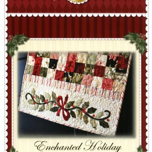 May include: A quilted table runner with a patchwork design in red, green, and black squares. The bottom edge features a holly and bow design. The text "Enchanted Holiday Table Runner" is displayed below the runner. The brand name "Shabby Fabrics" is at the top.