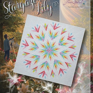 May include: A white quilt with a colorful starburst design. The quilt features a central star pattern with radiating points in shades of red, yellow, blue, and green. The quilt is labeled "Stargazer Lily" and "Free Spirit True Colors by Tula Pink".
