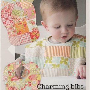 May include: A patchwork baby bib with floral and geometric patterns. The bib is shown on a baby in a high chair. The image includes the text "Charming bibs" and "big bibs for little ones". The bibs are made by "thimble blossoms".