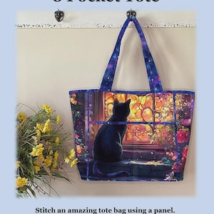 May include: A tote bag featuring a black cat sitting by a window with a colorful floral garden view. The bag has two shoulder straps and a galaxy-patterned trim. Text reads: Playing with Panels 8 Pocket Tote. Finished Size 12 inches high x 18 inches wide x 6 inches deep.