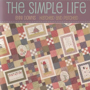 May include: A quilt with a patchwork design in shades of red, brown, and beige. The quilt features framed images with illustrations of a turtle, a house, and other whimsical designs. The text "THE SIMPLE LIFE" is displayed at the top.