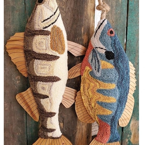 May include: Two handmade fish wall hangings. One is beige and brown, the other is blue, orange, and red. Both have wooden fins and tails. The fish are suspended by rope. The text at the bottom reads "Fish Tails Blue Gill & Walleye."